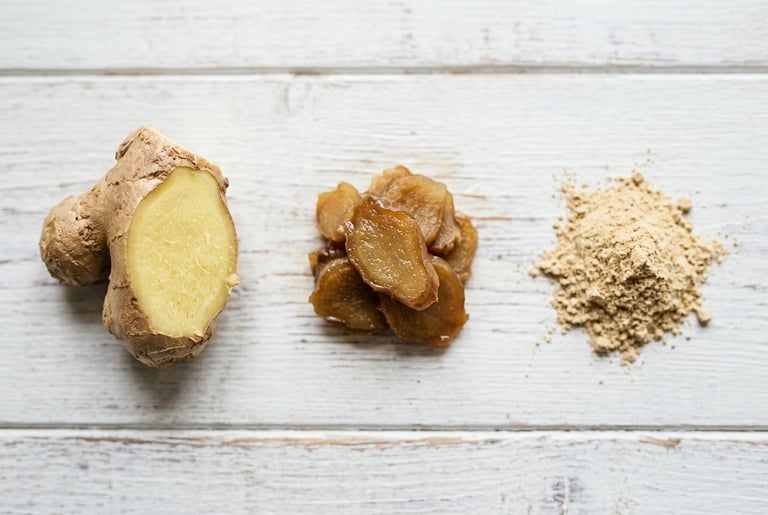 A piece of fresh ginger cut to show its pale yellow fibrous flesh, a pile of cooked translucent ginger slices, and a heap of fine ground dried ginger, laid out in a row