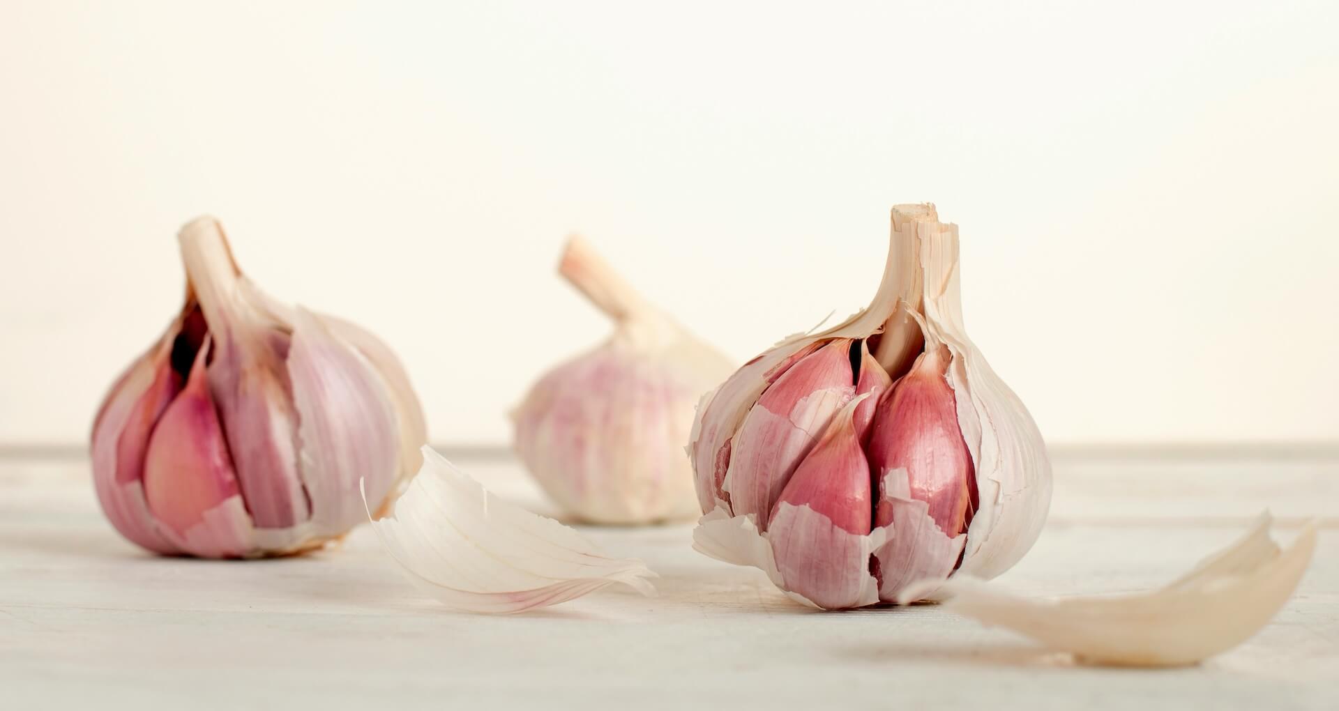 Garlic bulbs and cloves scattered on white surface